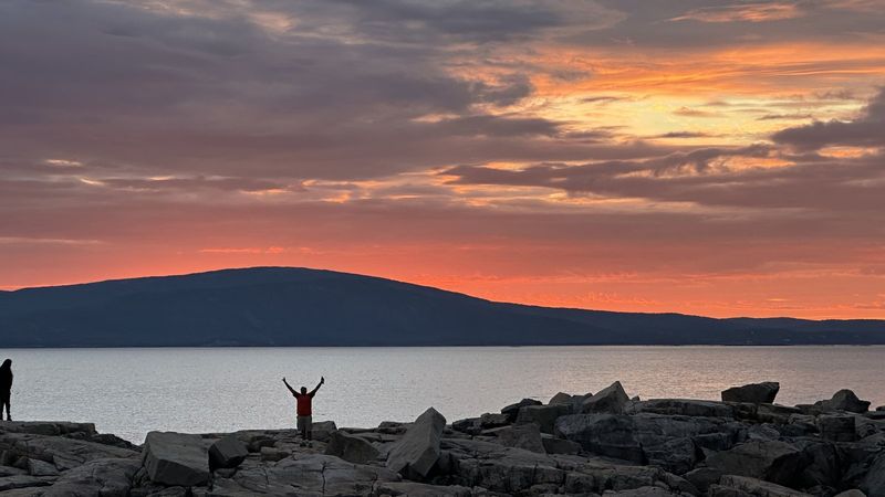Orange sunset over the water and rocks in Maine